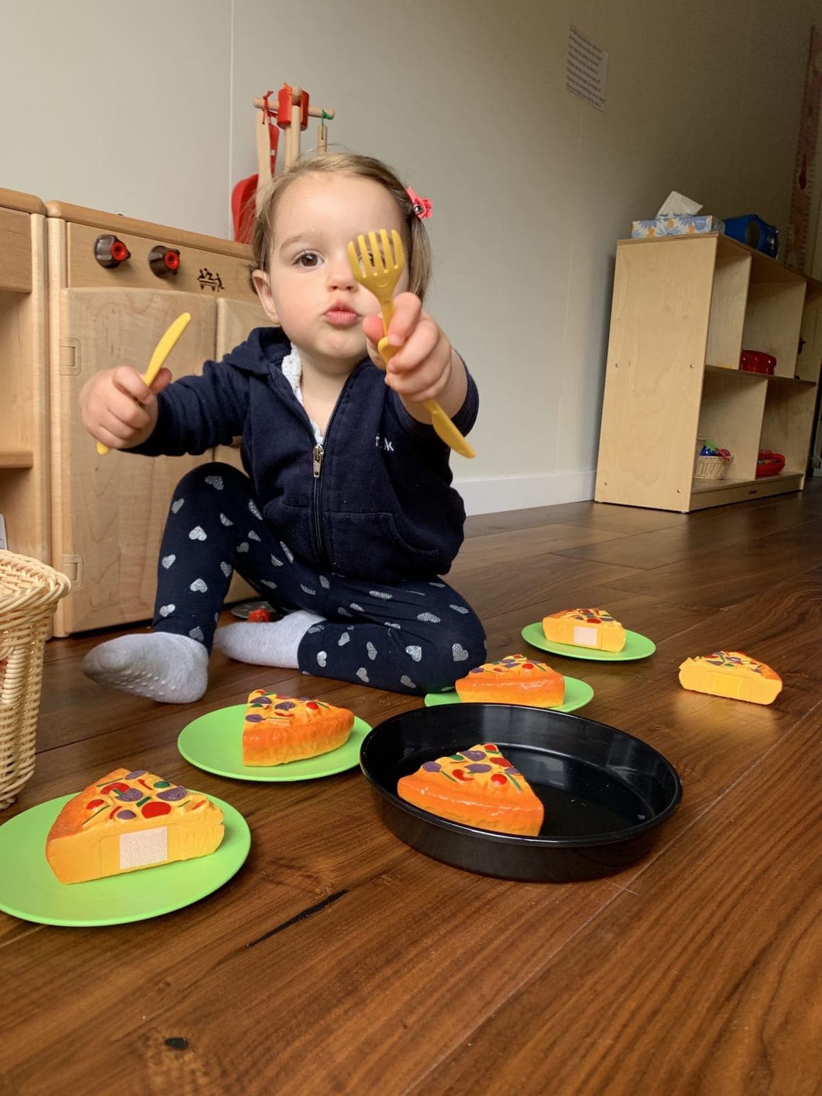 A toddler playing with a toy food set during indoor playtime at Wisely SF